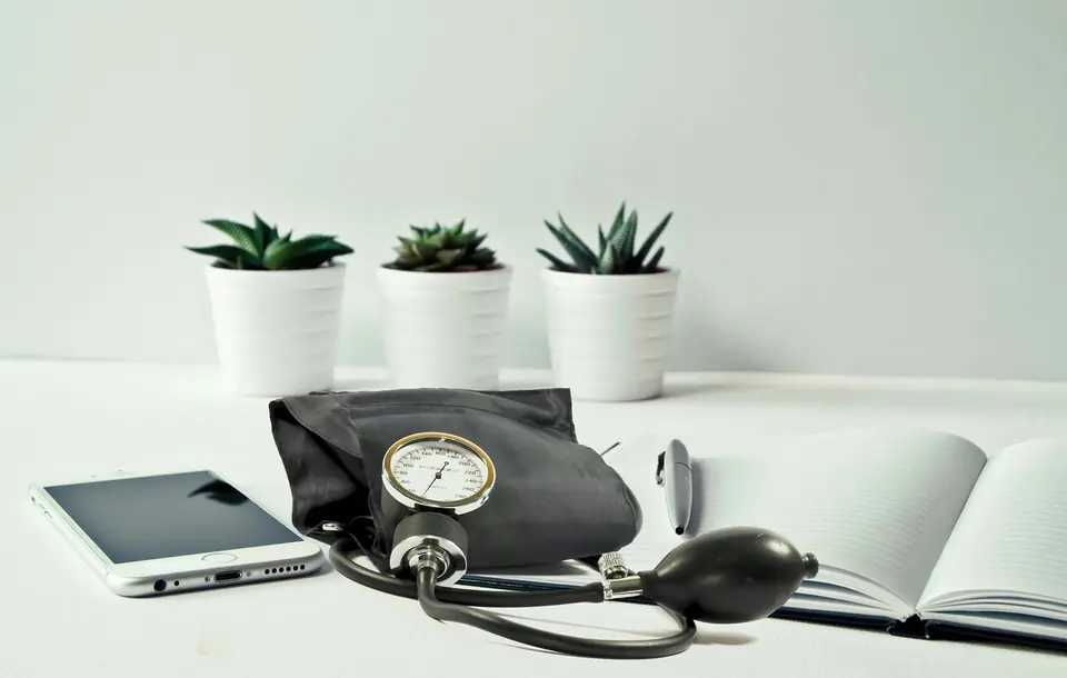 A blood pressure monitor on a desk beside a notebook