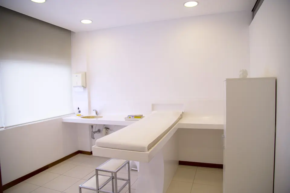 A clean, empty clinic treatment room with an examination bed